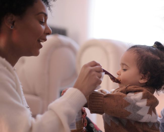 A mother using a spoon to feed her child